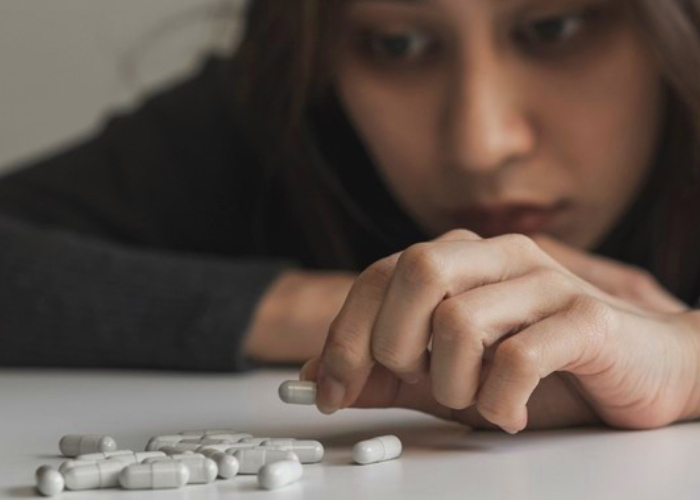 Troubled woman looking at her medicines