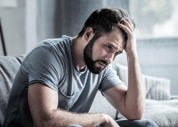 Adult male holding his head due to over thinking