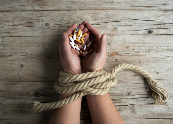 hand holding different kinds of medication with rope on the wrist