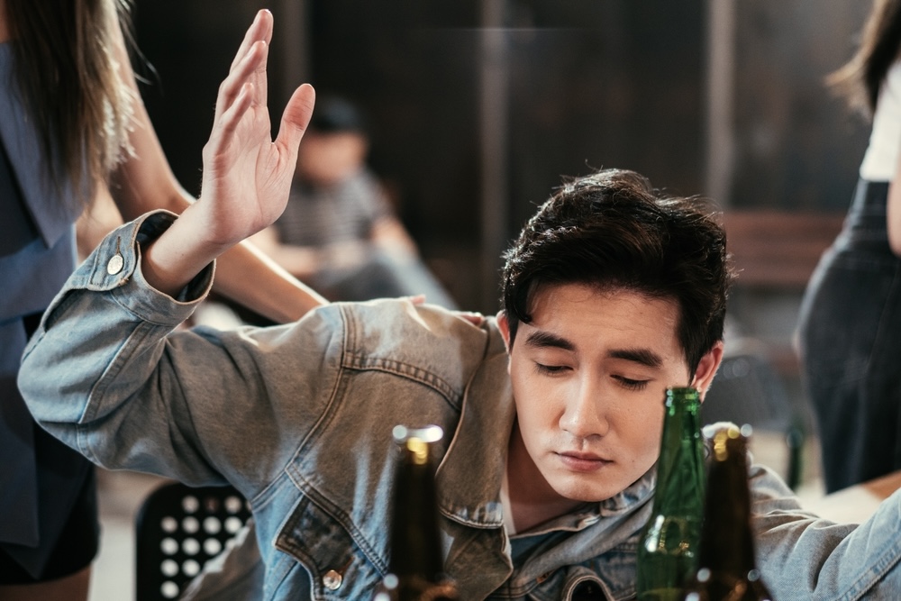 A drunk man in front of bottles of beer