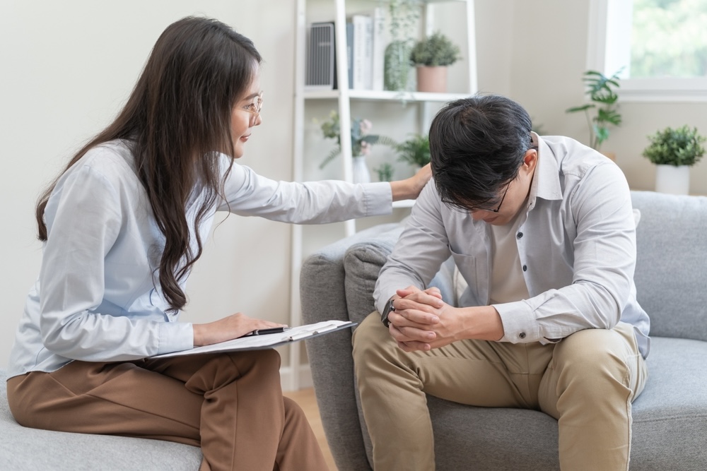 A stressed man talking with a psychologist about addiction treatment